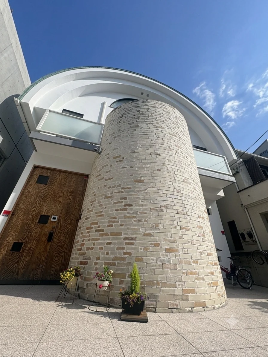 丸みのある石張りの壁と木の扉が見える建物の外観
