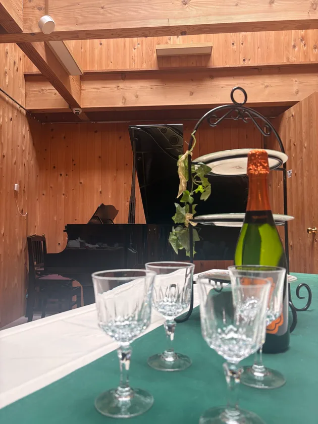 ピアノの前にテーブルとグラスを配したイメージ